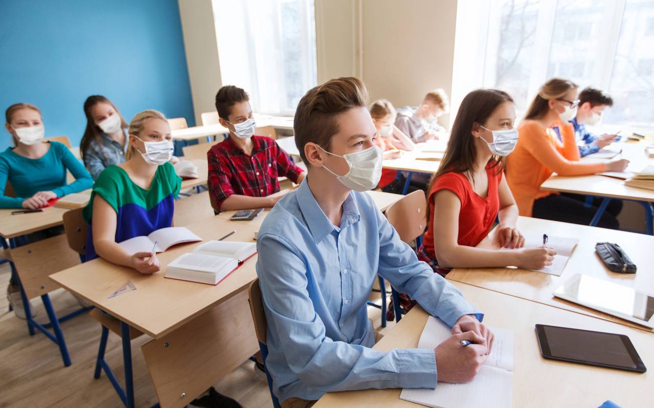 Schüler sitzen im Klassenraum und tragen einen Mundschutz.