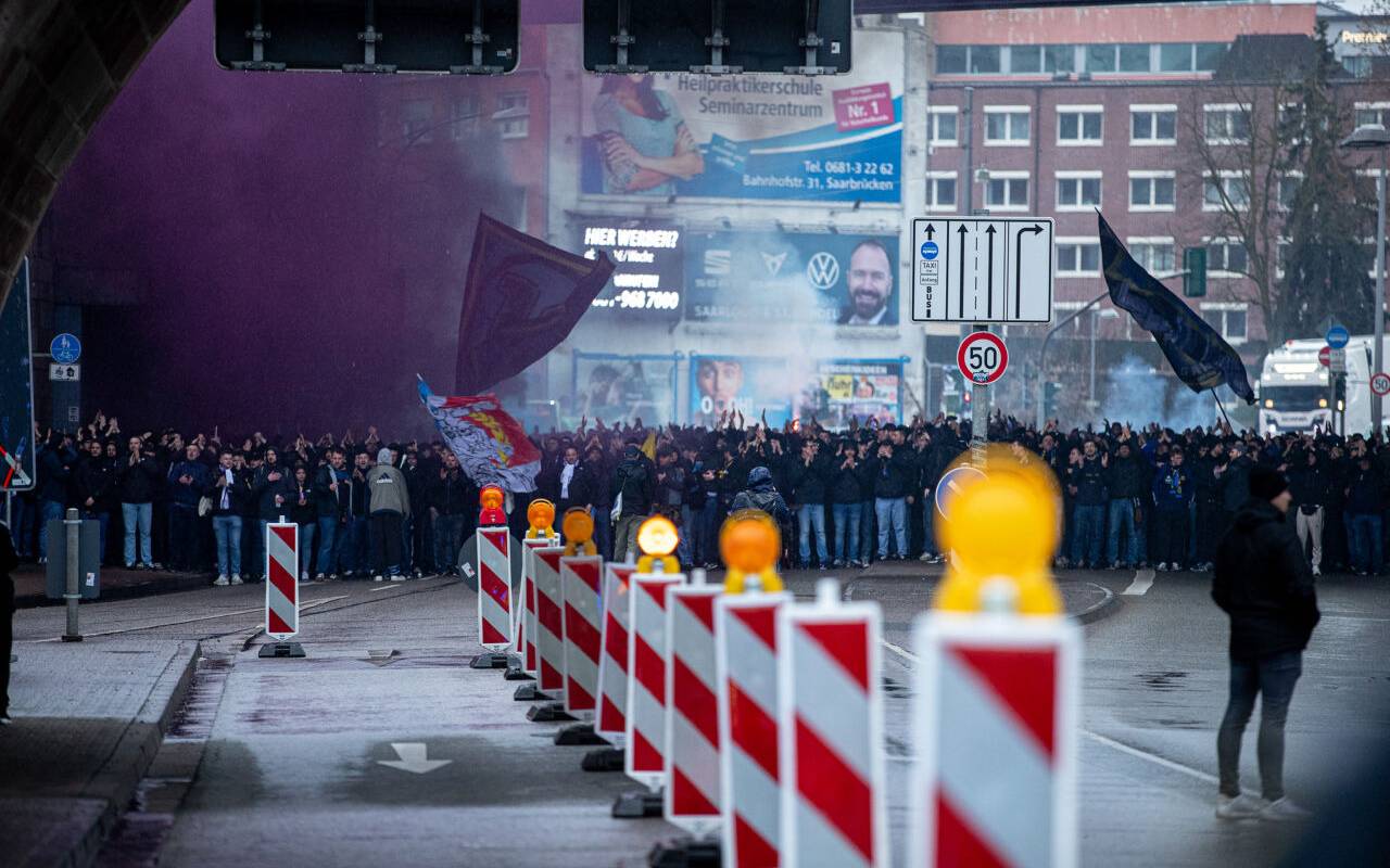Fußballfans stehen in einem Tunnel und werden von Polizisten begleitet.