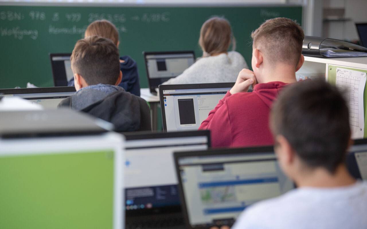 Beschreibung Schülerinnen und Schüler nehmen im Klassenzimmer einer 9. Klasse der Gemeinschaftsschule Leutenbach am Geografieunterricht mit Hilfe von Laptops und Tablets teil.