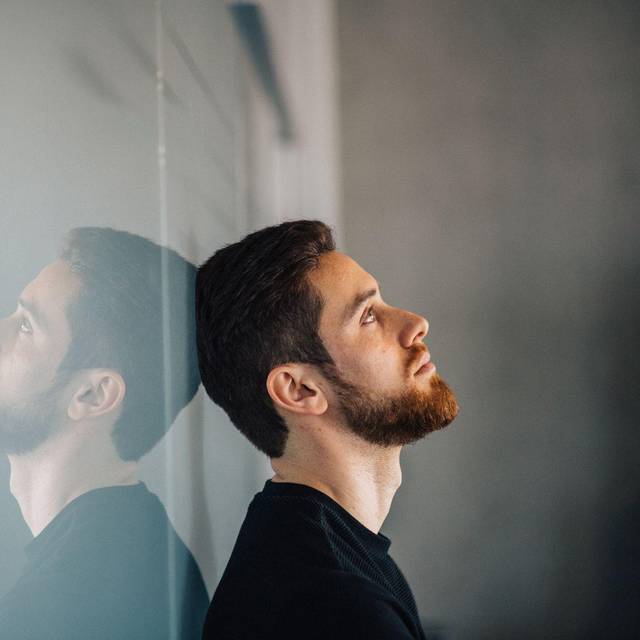 Ein junger Mann lehnt nachdenklich an einer Glaswand