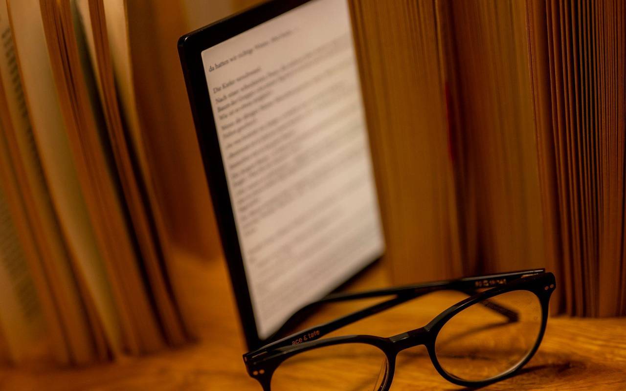 E-Book-Reader steht zwischen Büchern auf einem Tisch