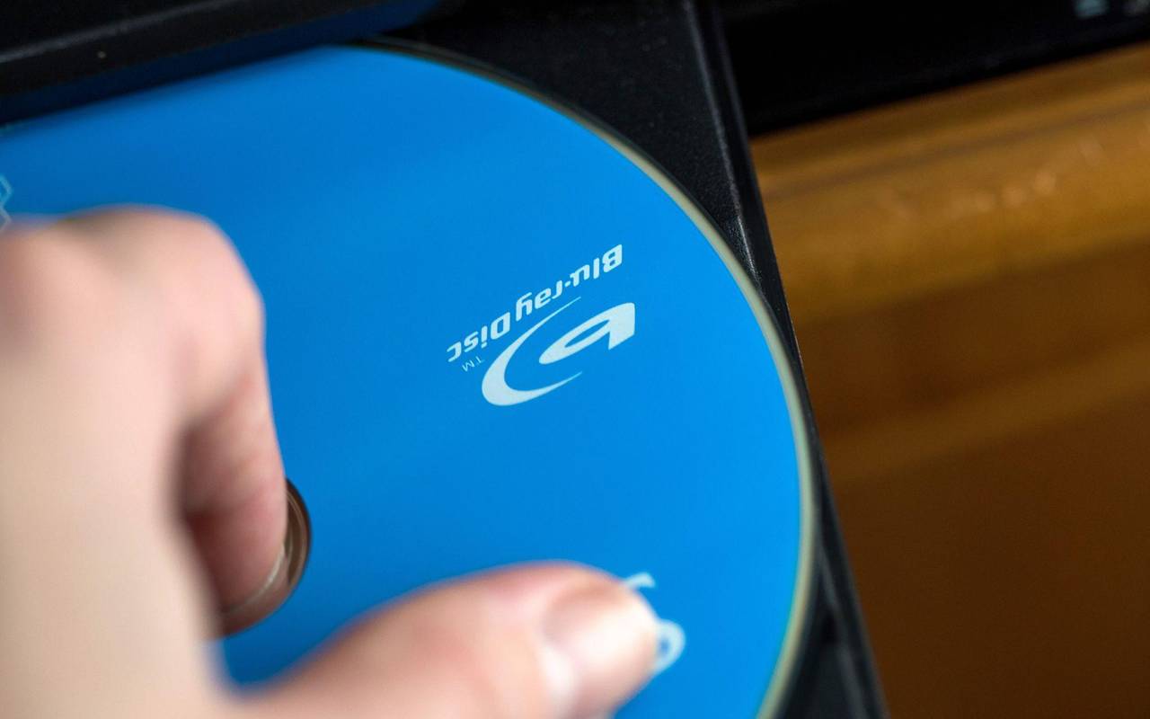 Eine Frau legt eine Disc in einen Blu-ray-Player