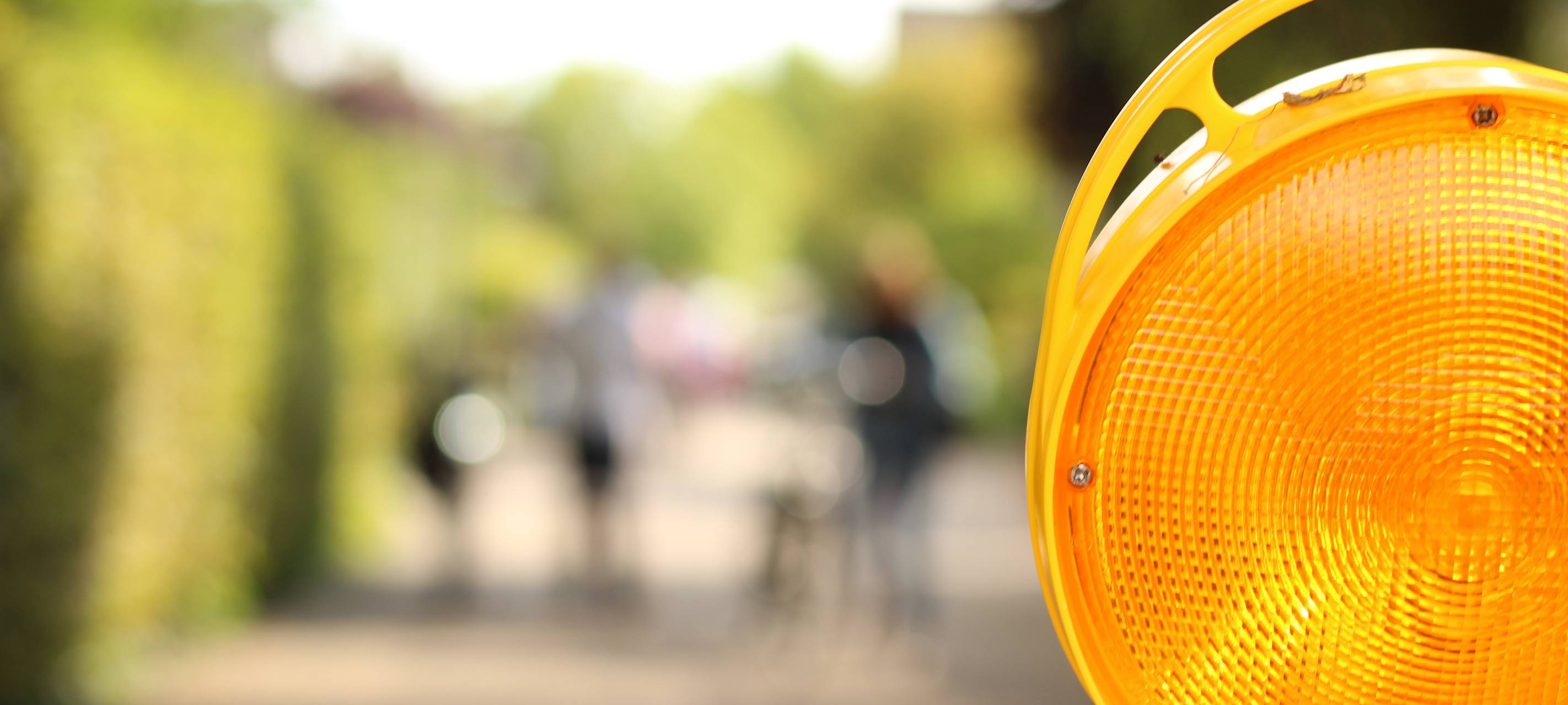 Eine Nahaufnahme einer gelb blinkenden Warnleuchte im Straßenverkehr, die zum Beispiel bei Sperrungen verwendet wird.