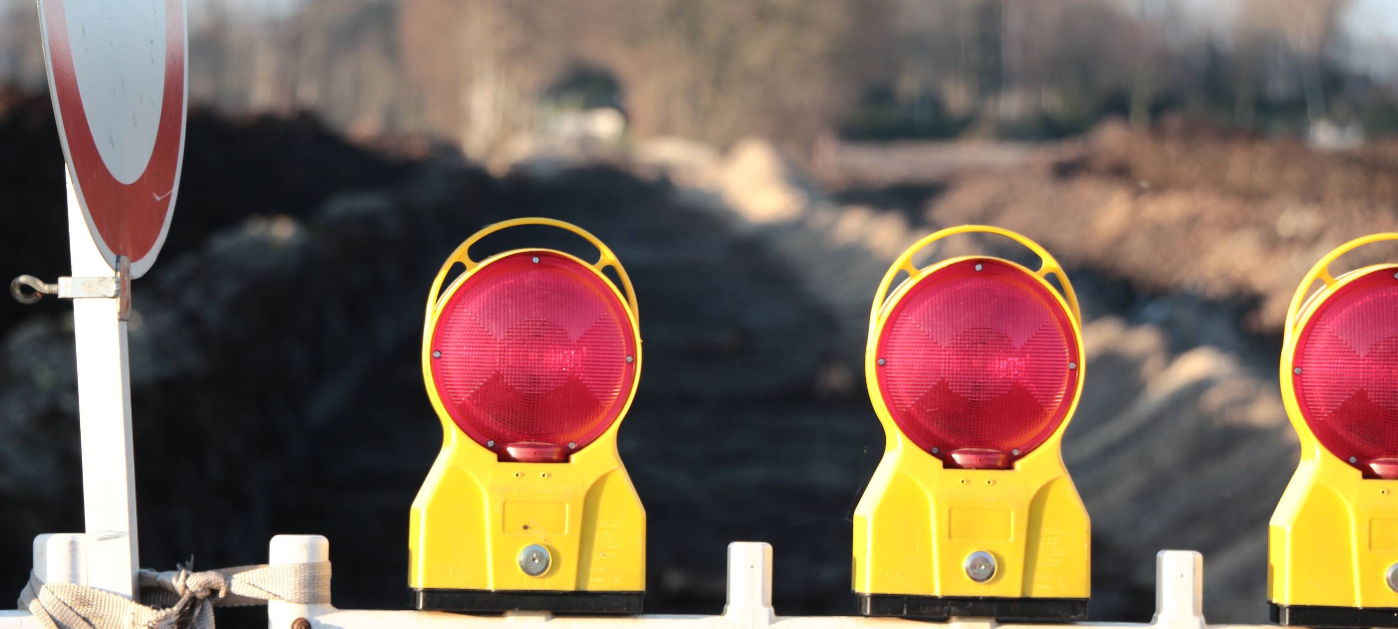 Eine Straßensperre steht im Vordergrund des Bilds, im Hintergrund sieht man unscharf die Baustelle einer neuen Straße.