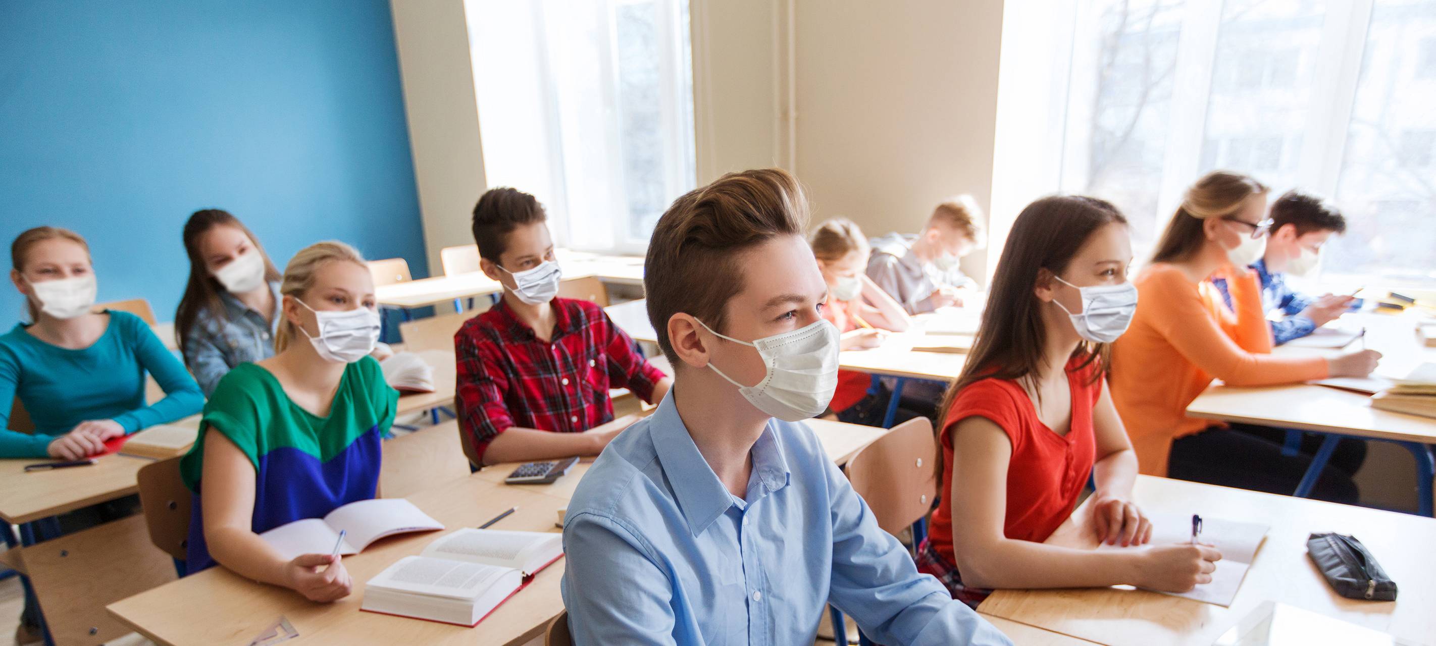 Schüler sitzen im Klassenraum und tragen einen Mundschutz.